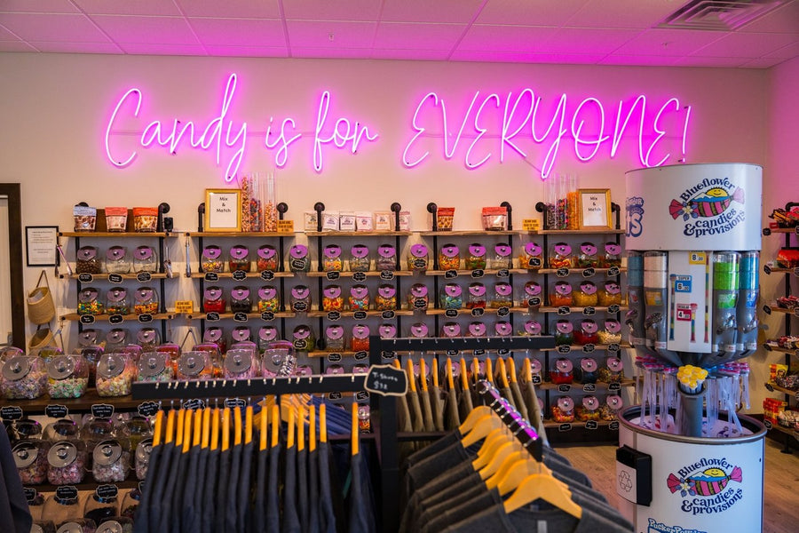 Buena Vista shop with a bulk candy wall under a pink neon sign reading Candy is for Everyone