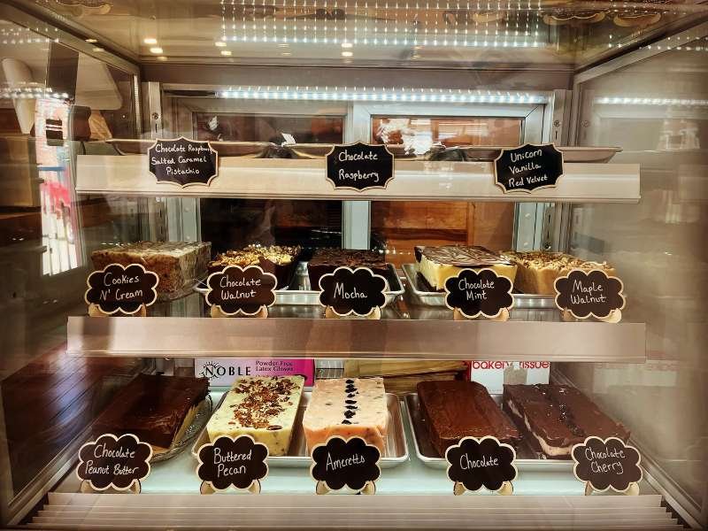 A glass case of fudge slabs with chalkboard flavor labels