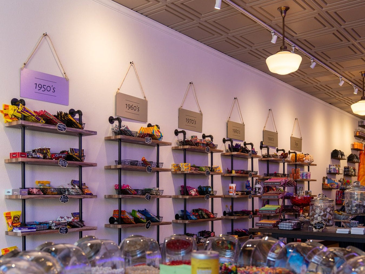 The candy wall in the Salida shop, with retro candy under hanging signs for the 1950s, 1960s, 1970s and 1980s